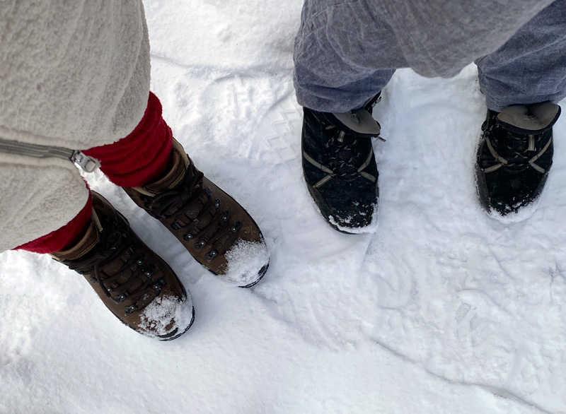 Portrait von zwei Füßen mit Wanderschuhen im Schnee.